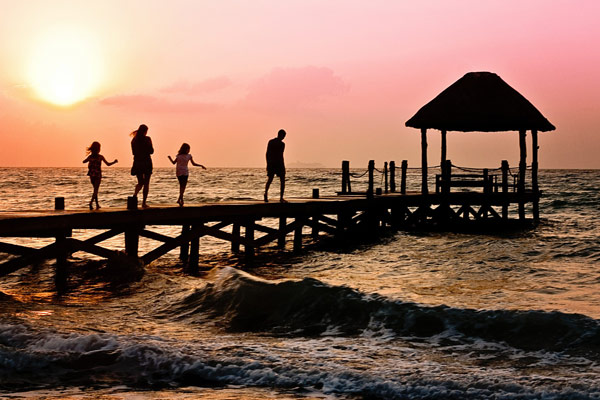 Family walking on a pier over the ocean at sunset 600