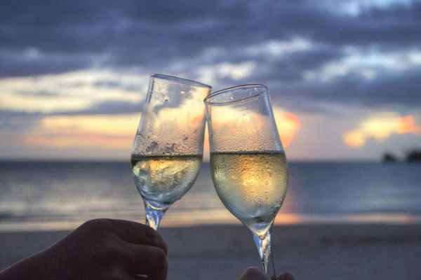Couple sharing champagne on a secluded beach at sunset 600