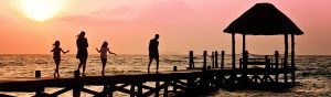 Family walking on a pier over the ocean at sunset 1200