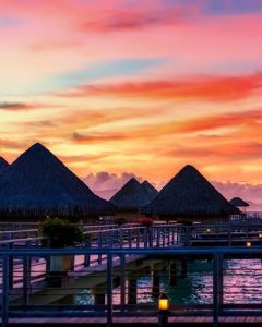 Bungalows under a sunset sky with mountains in the background at Bora Bora 400