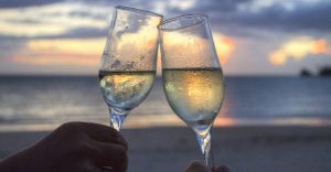 Couple sharing champagne on a secluded beach at sunset 960